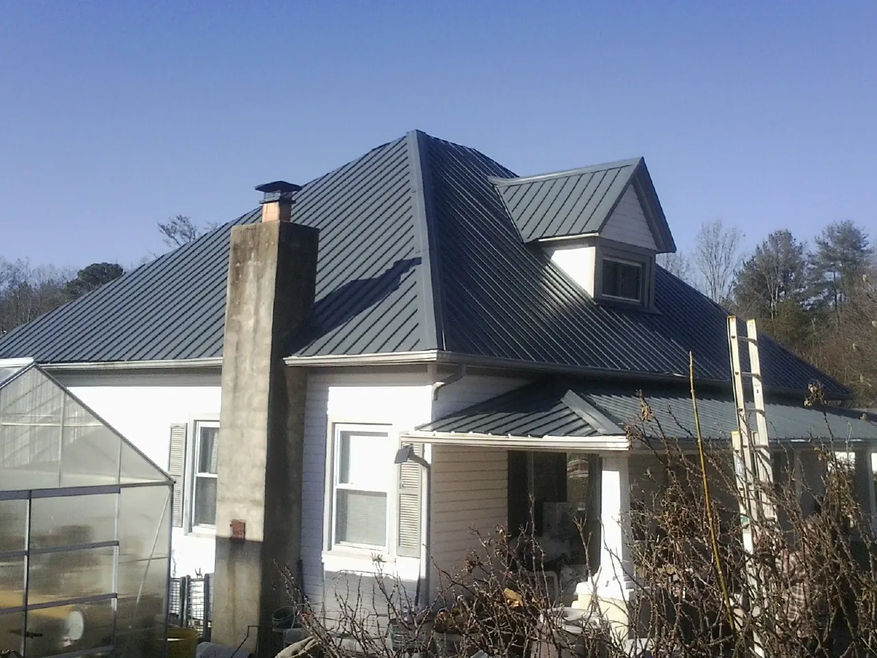 Dark blue standing seam metal roof on a white farmhouse with dormer — Slate & Tile Roof Repair by Roofing Brothers in Sycamore