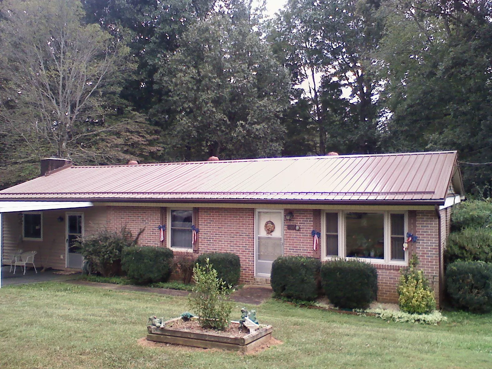 Bronze metal roof on a brick ranch home with a carport in Sycamore