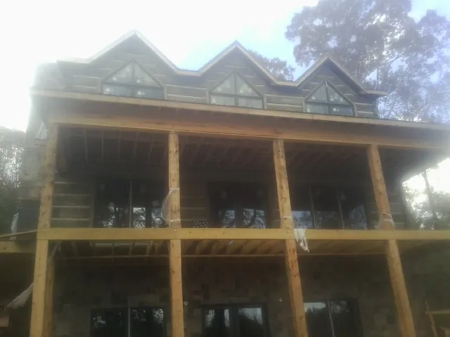 Dormers and porch framing on a large log home under construction — Roof Coating work by our crew in Sycamore