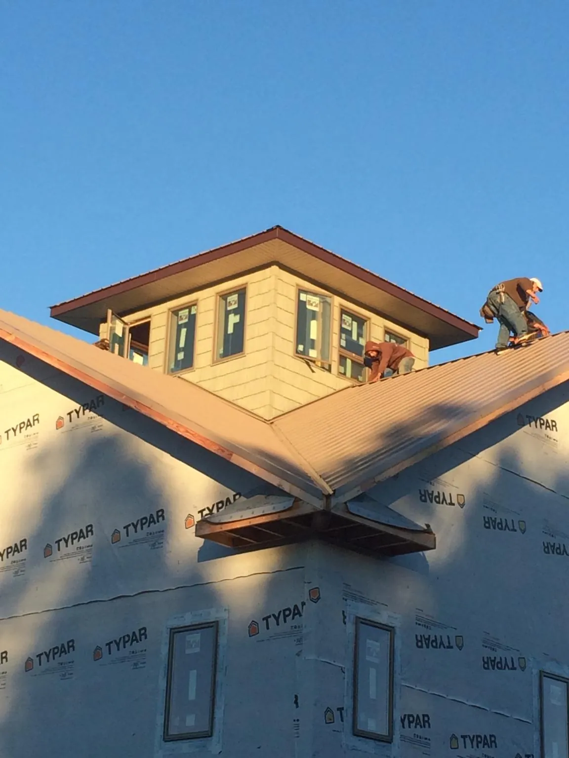 Roofers working around a rooftop cupola on a new metal roof at sunset — Roof Waterproofing in Sycamore by Roofing Brothers